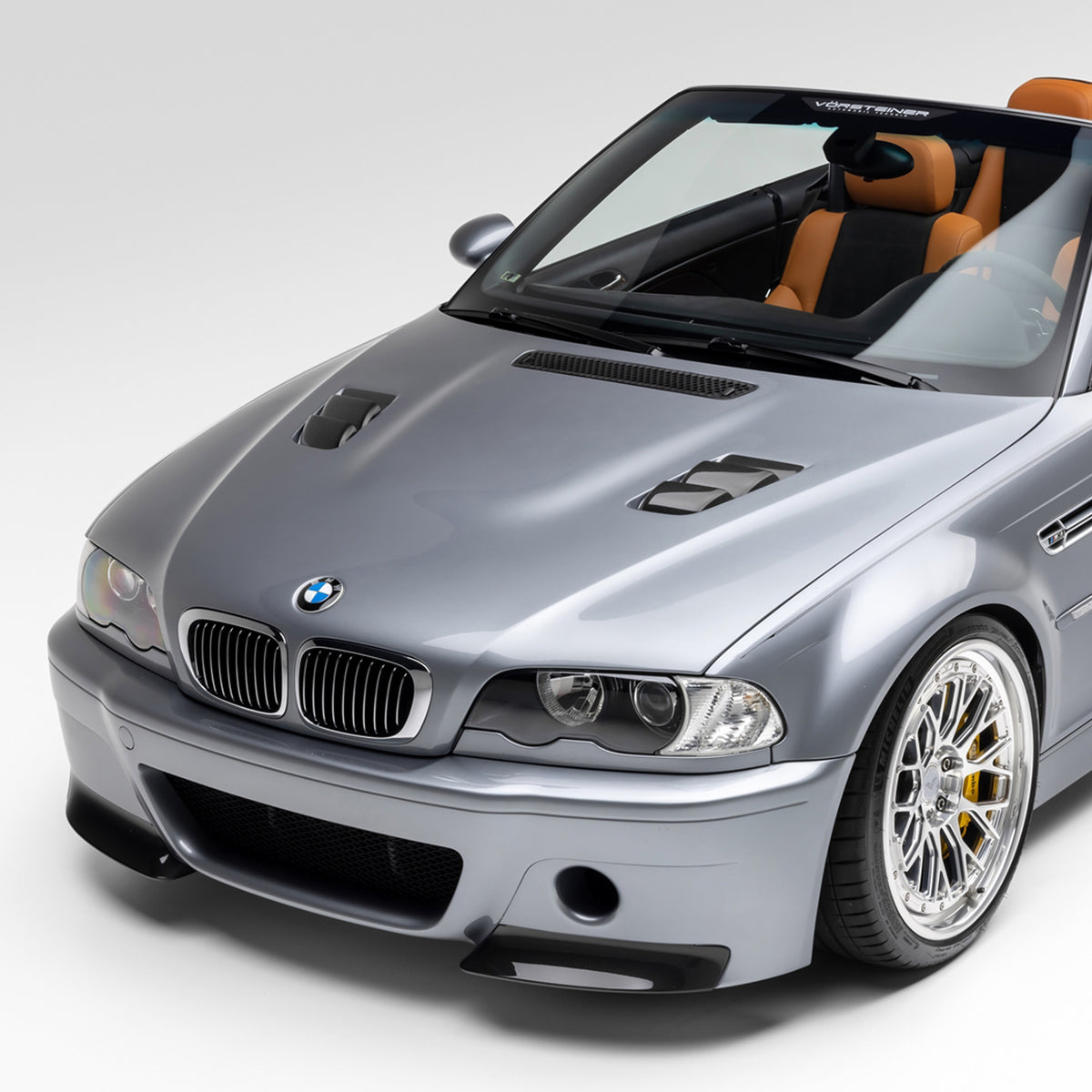 Glossy black carbon fiber vented hood for BMW E46 M3 V20 Aero by Vorsteiner, showcasing aerodynamic design and lightweight construction.