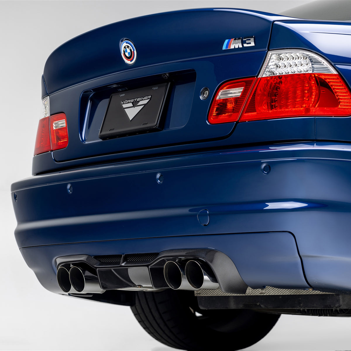 BMW E46 M3 V20 Aero rear diffuser by Vorsteiner, glossy 1x1 carbon fiber finish, enhances sporty rear aerodynamic look.