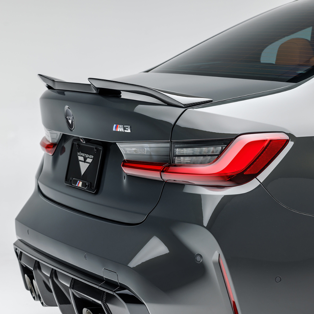 BMW G8X M3 carbon fiber V-Style Aero decklid spoiler by Vorsteiner Aerodynamics, installed on the car's rear for enhanced sporty appearance